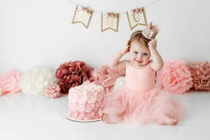 Happy baby girl in pink tutu dress celebrating first birthday with a pink smash cake by babies first birthday photographer in Menifee.
