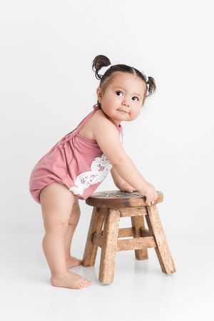 Baby girl in pink romper in 1st birthday photography session.