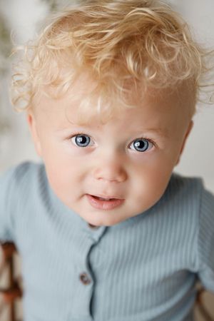 Child portrait photography: Cute toddler with curly blonde hair and blue eyes.