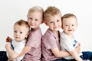 Twin brothers holding other set of twin brothers in bright white photography studio in Menifee.