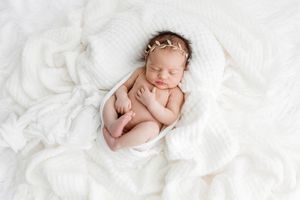 Newborn photo by Emily Menzie Photography: Cute baby girl sleeping on cream blankets.