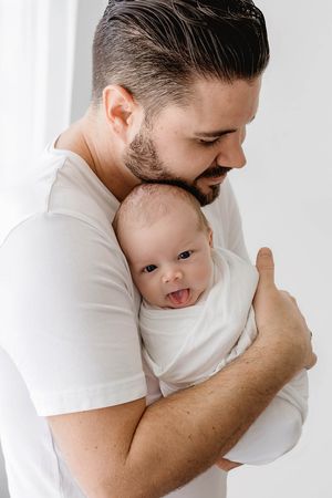 Dad holding newborn baby boy by photographer in Murrieta.