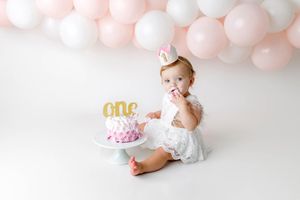 First birthday cake smash photography session in Menifee - cute baby girl with cake and balloons.