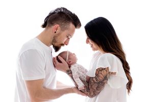 Bright white timeless professional newborn photography - parents holding baby daughter.