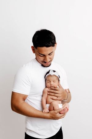 Daddy daughter photoshoot of dad holding his sleeping newborn baby girl.