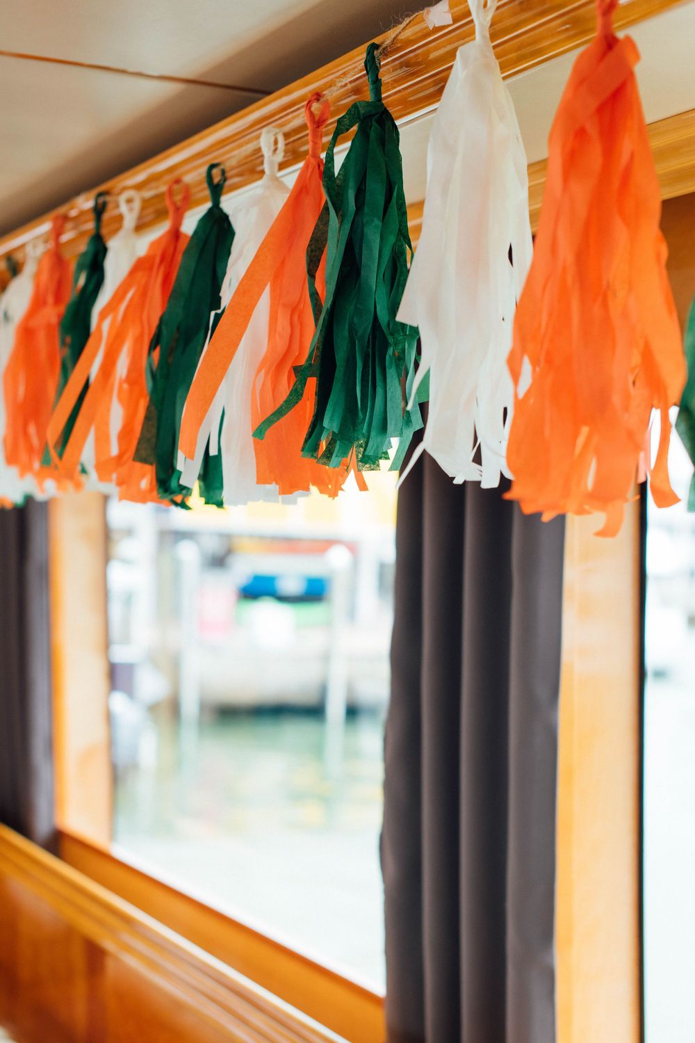 Colorful orange, green, and white paper tassel garland hanging as festive decoration on a boat interior.