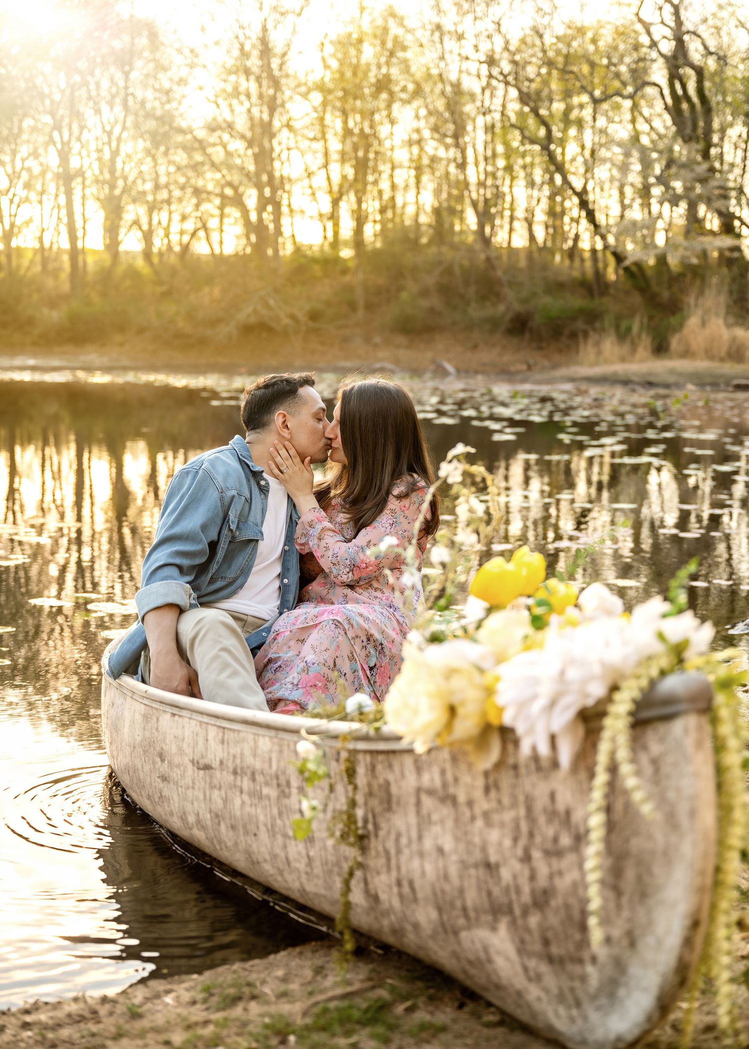 A romantic proposal scene set between rows of grapevines in a scenic vineyard with white flowers and a blanket.