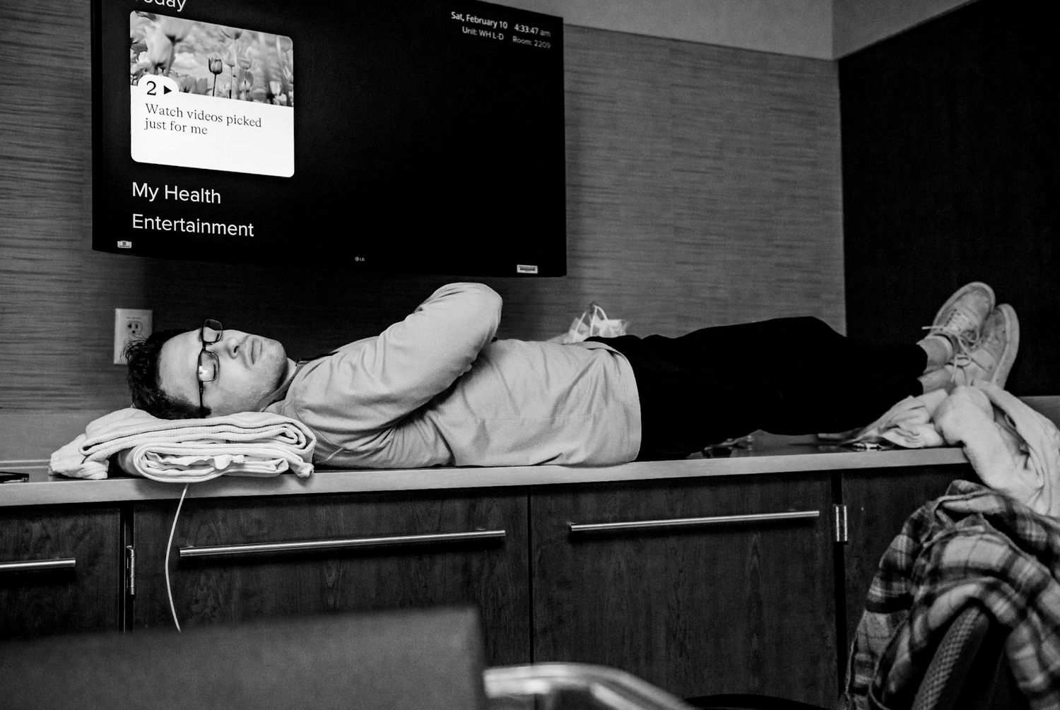 Black and white photo of exhausted support person resting on hospital room counter during labor.