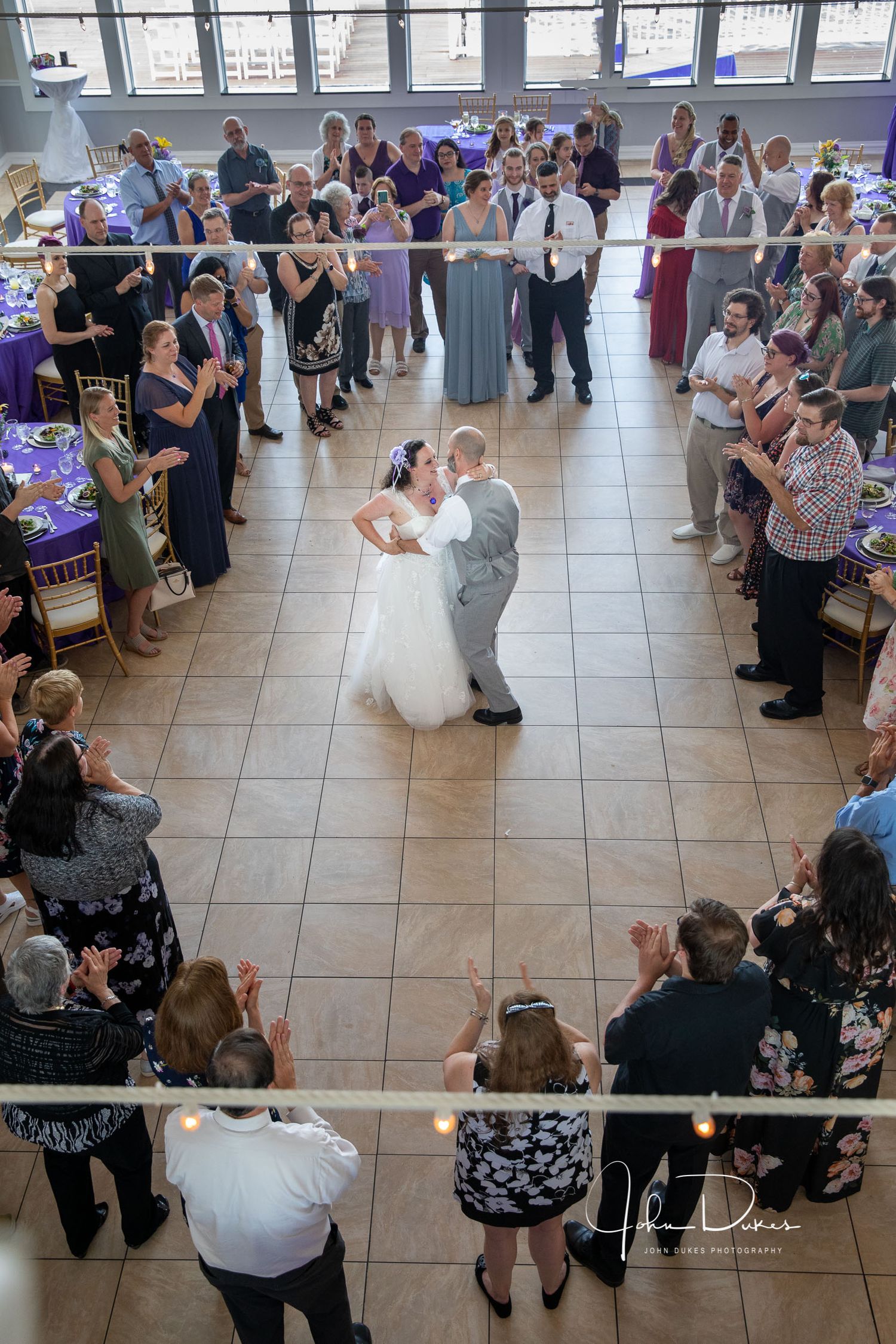 Bride and groom share first kiss at church altar, groom wearing Scottish kilt, bride in white gown with veil and floral crown.