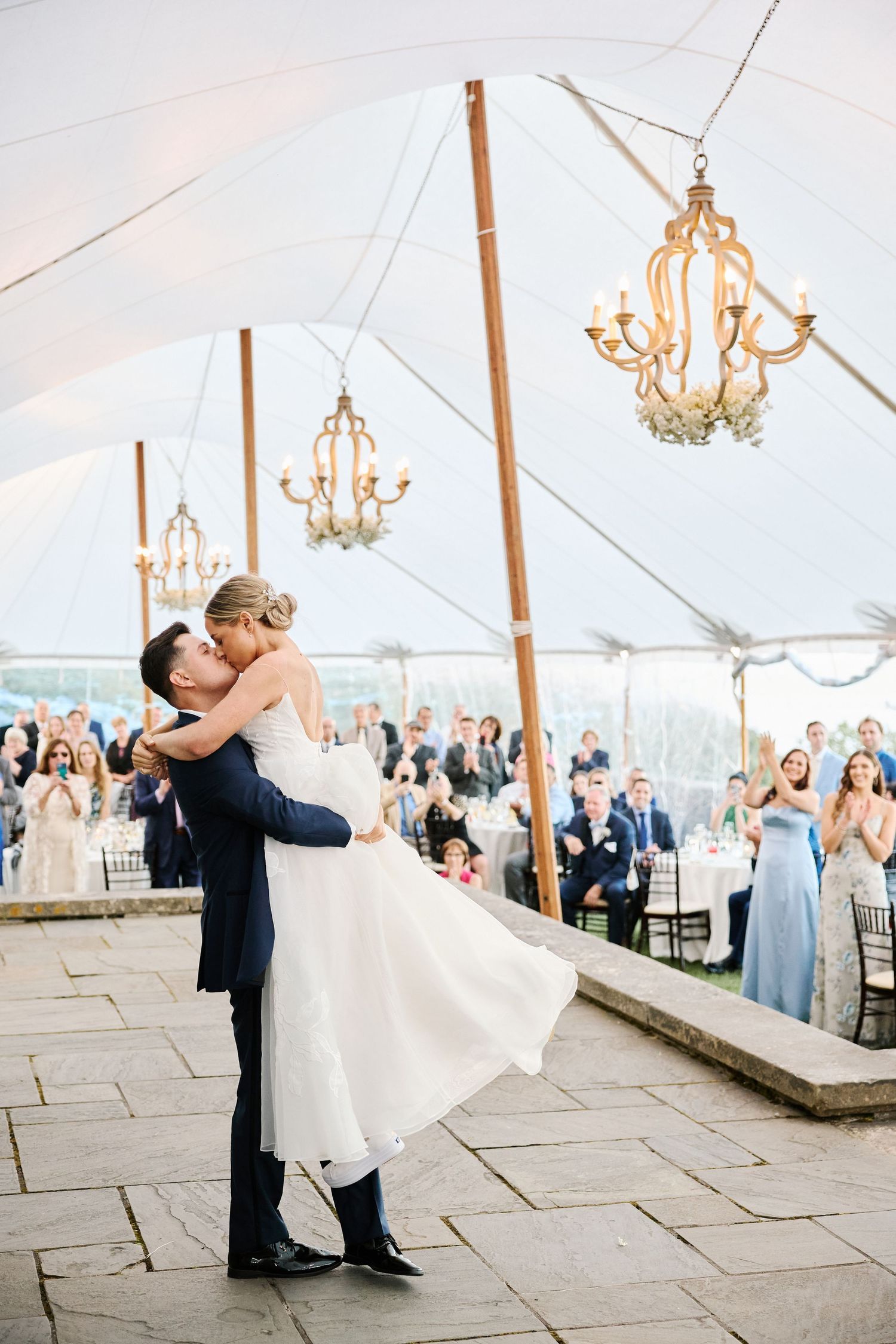A romantic first dance under chandeliers in a white tent at an outdoor wedding reception at Crane Estate.