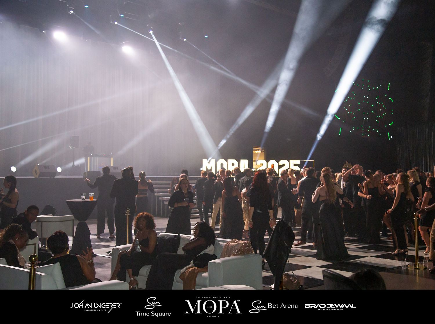 Elegant evening gala event with guests mingling under dramatic stage lighting at a MOPA branded venue.