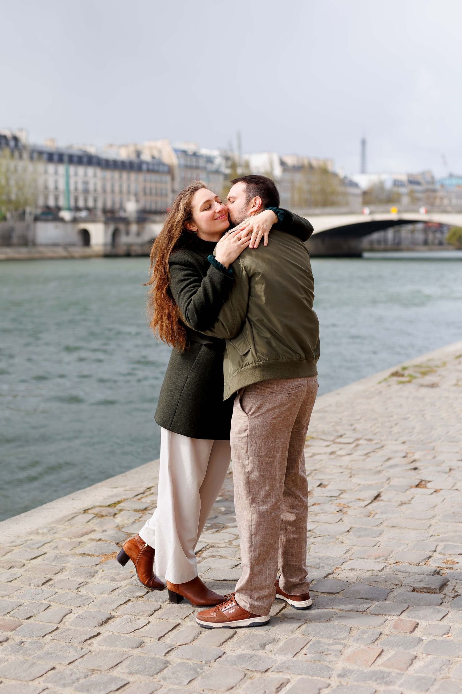 Couple sharing a romantic embrace in an elegant Parisian arcade with classical stone arches and columns.