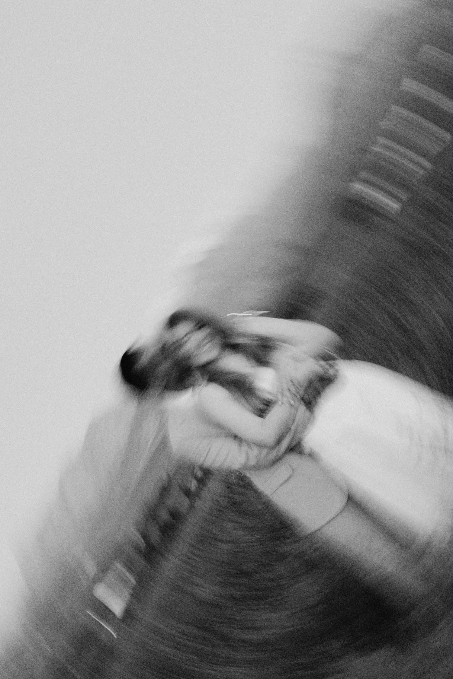 Blurred black and white motion photo of a person spinning on a carousel, creating an abstract swirl effect.