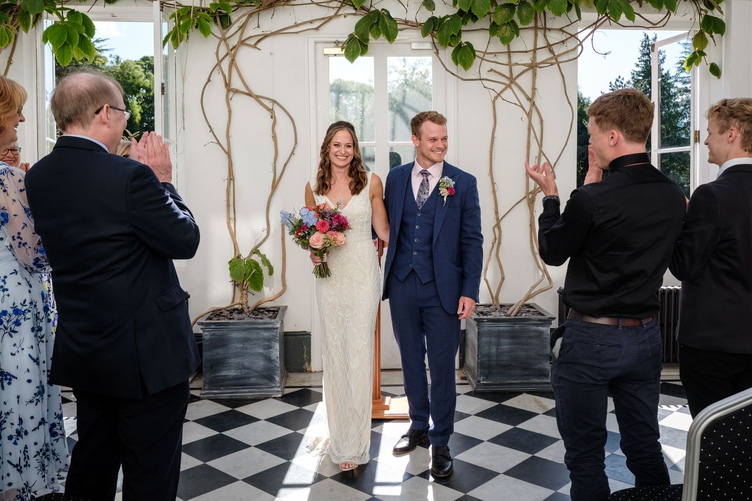 A large group of people, including a bride and groom, posing together outside a building.