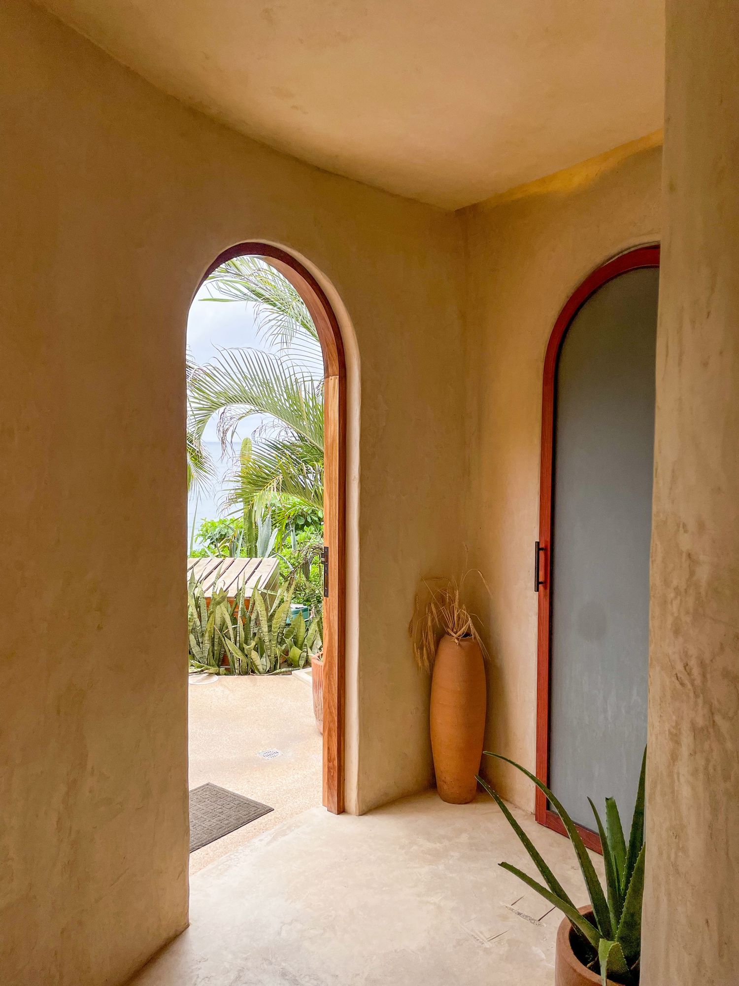 Serene rooftop terrace with rustic wooden stools, cushioned bench, and lush tropical palm trees in Sayulita, Mexico.
