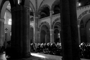 Black and white photo of congregation seated inside a grand historic church with tall stone columns and arched ceilings.