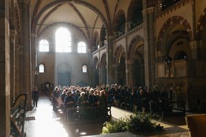 Congregation gathered inside a grand historic church with arched ceilings and sunlit windows during a ceremony.