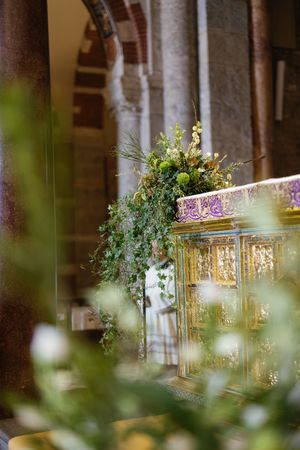 Golden ornate church altar adorned with lush green ivy and floral arrangements in an elegant historic cathedral.