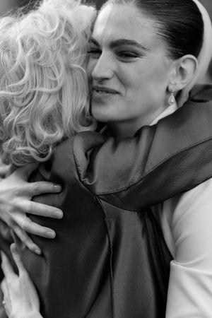Black and white photo of two women sharing a warm embrace at a wedding celebration.