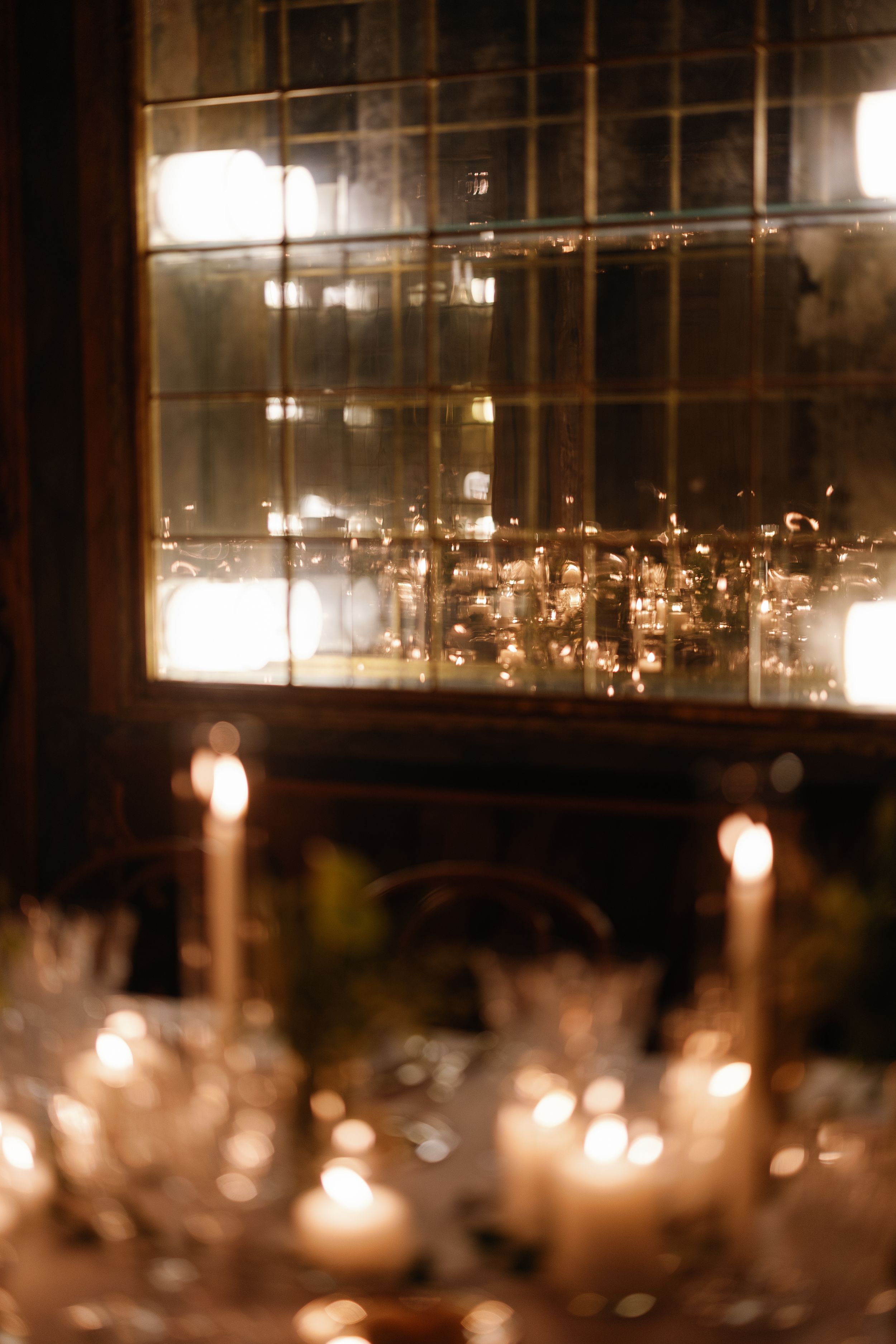 Romantic candlelit wedding reception table with glowing candles reflected in antique mirror.