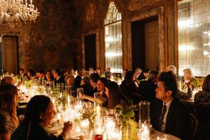 Guests seated at candlelit wedding reception dinner in grand ornately decorated ballroom.