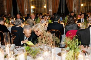 Wedding guests seated at candlelit reception tables in a grand ornate ballroom.
