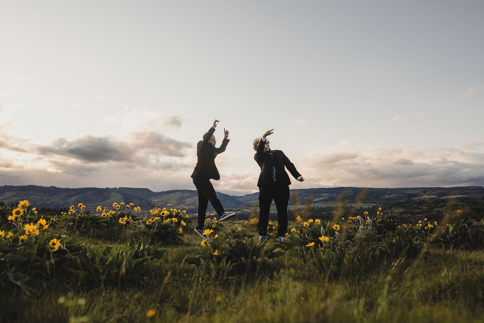 Eloping couple dancing joyfully at Rowena Crest,  in a field of yellow wildflowers at dusk with views of the gorge in the background.