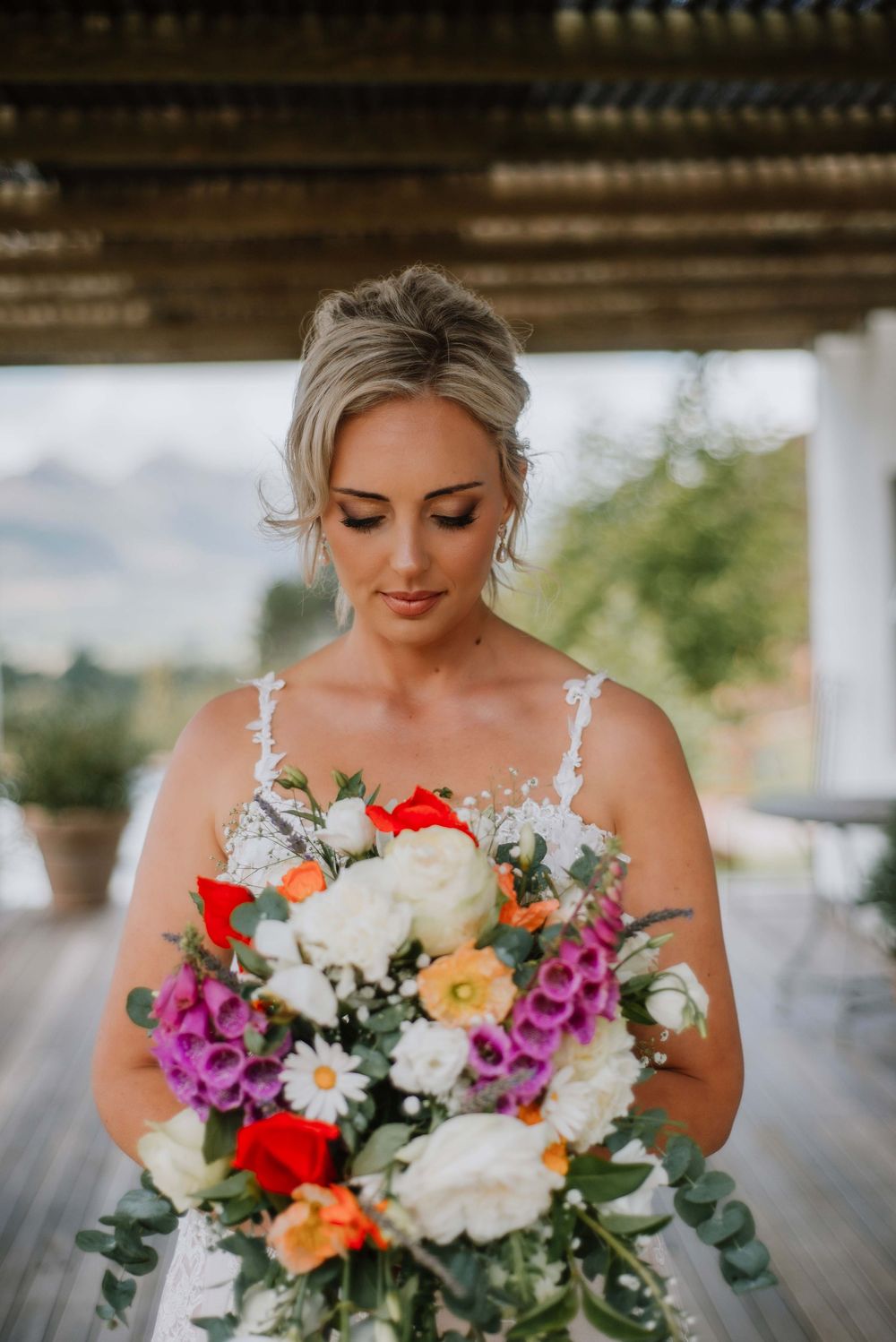 Bridal portrait of bride holding bright floral bouquet during wedding photoshoot in natural light