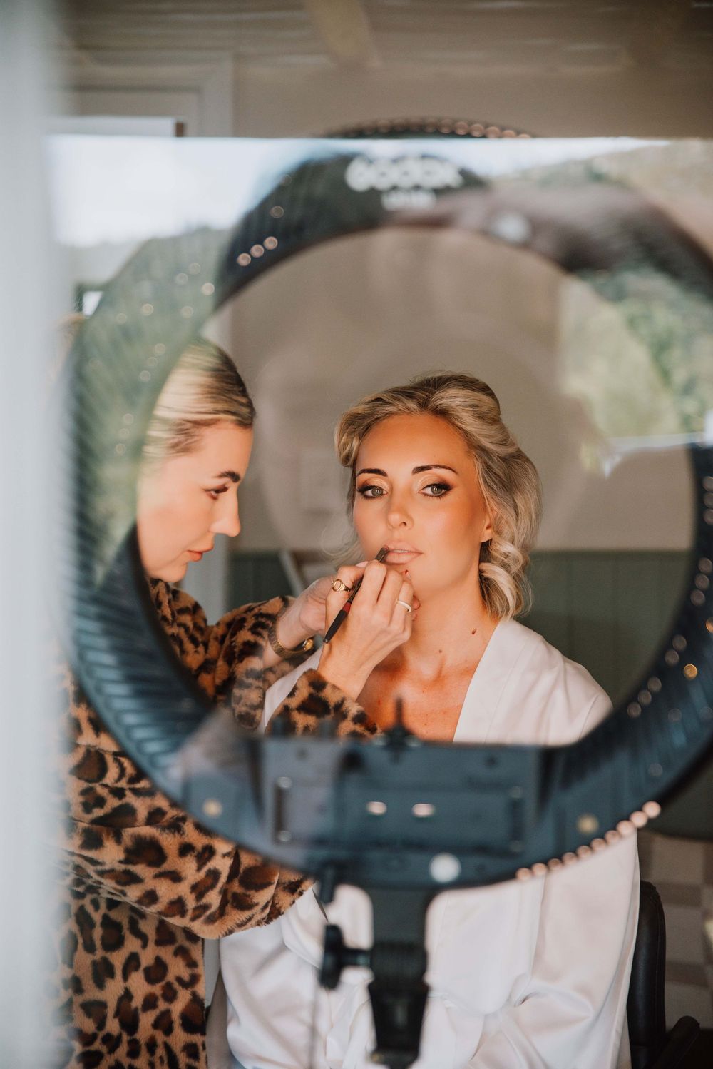Bride sitting in bridal suite getting makeup done by artist before wedding ceremony preparation