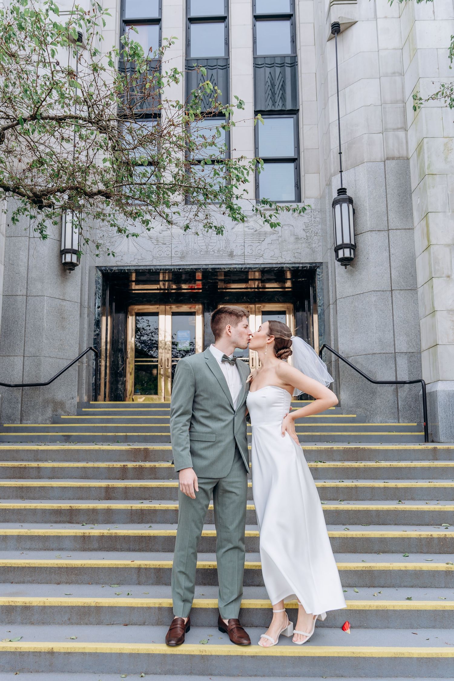 A series of photos showing a couple in wedding attire playfully walking down yellow-striped stone steps outside a building.