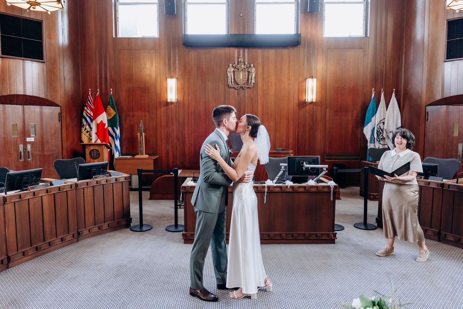 Wedding ceremony taking place in an elegant wood-paneled room with pendant lighting and large windows.