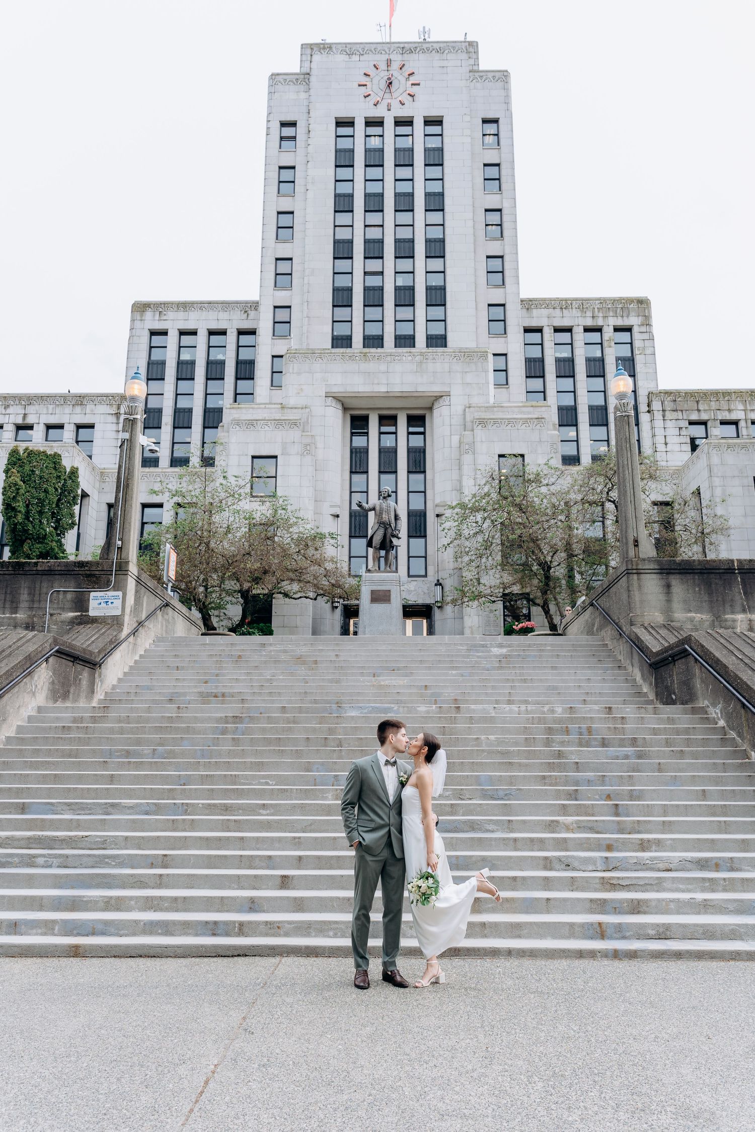 Couple standing on grand stone steps of historic art deco government building.