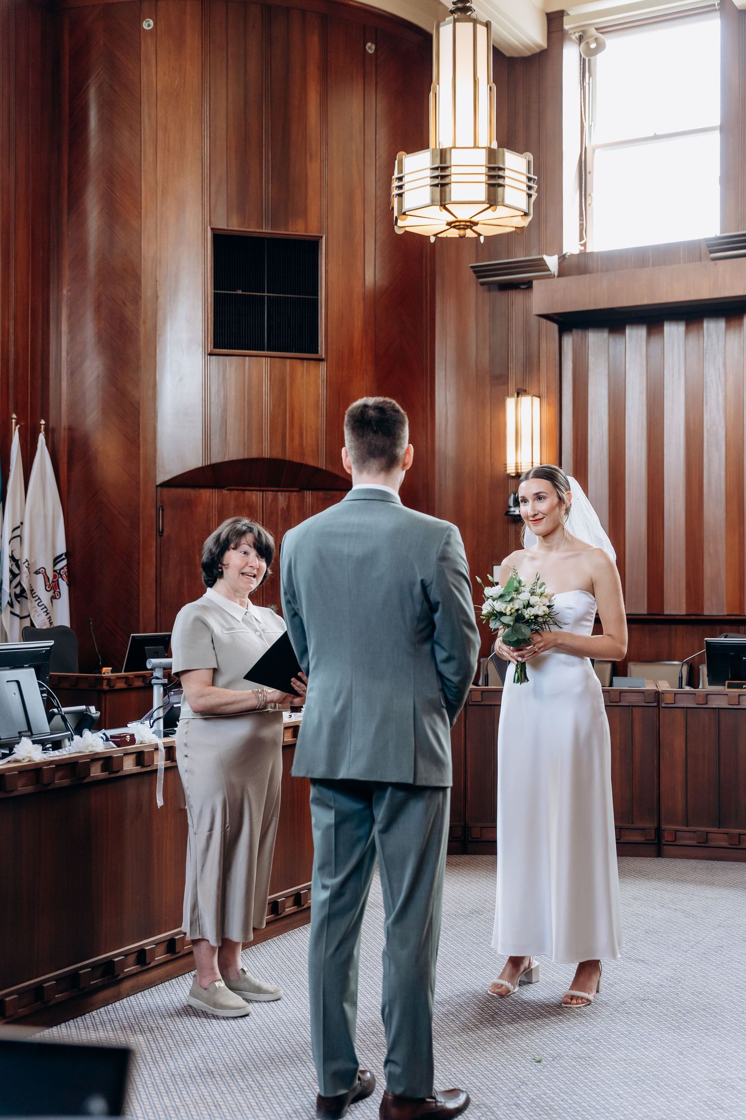 A sequence of four wedding ceremony photos showing moments between people in a wood-paneled room with vintage lighting.