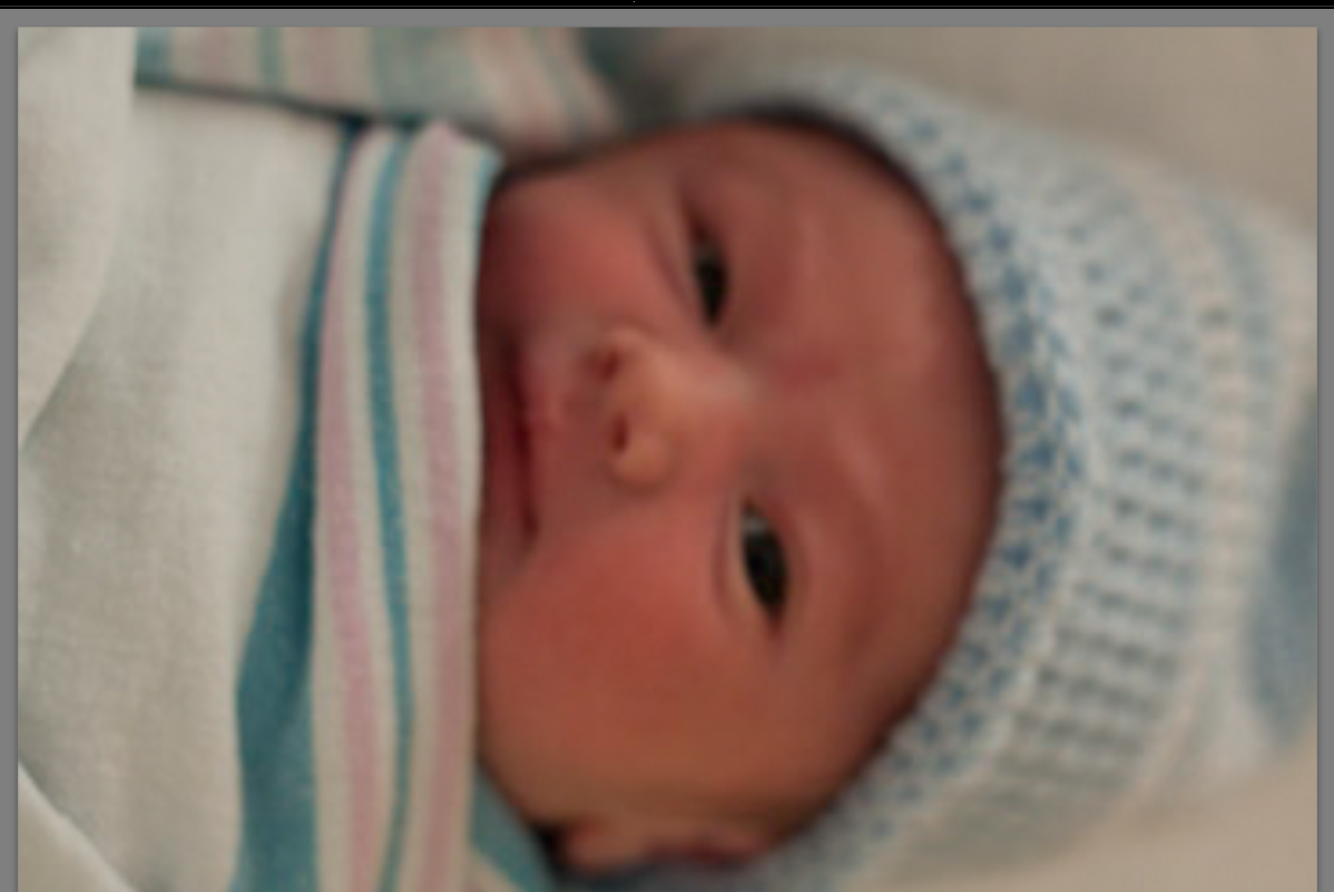 Marshall the day after he was born.  Lying on bed, all wrapped up with a big smile on his face.