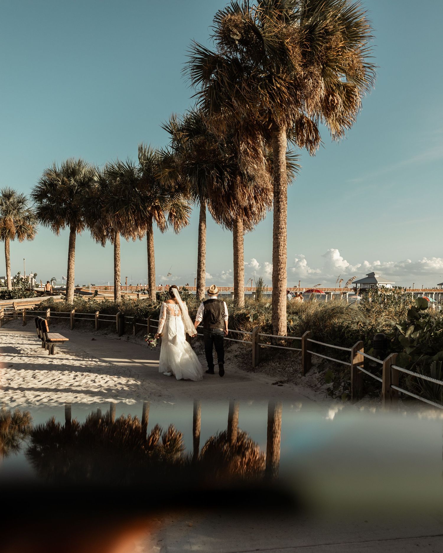A beach wedding photo with palm trees lining a sandy pathway.