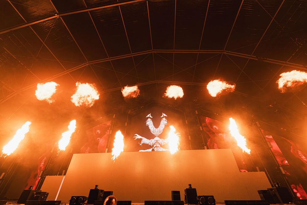 A row of bright flaming pyrotechnic effects illuminate a dark stage during a dramatic performance.