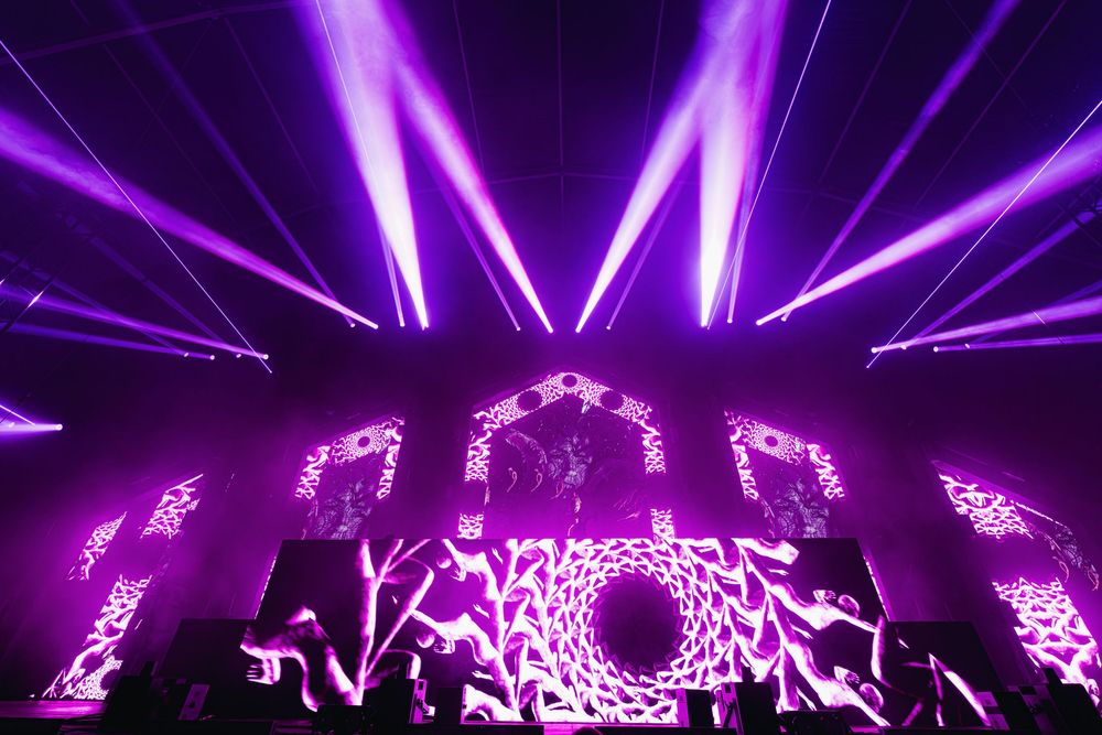 Purple laser beams and lights create a dazzling visual display during an EDM concert performance.