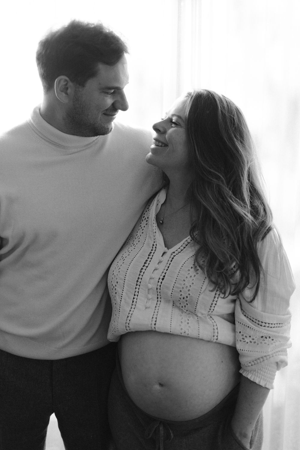 Progressive shots of an expectant couple in white clothing showing affection and the pregnant belly.