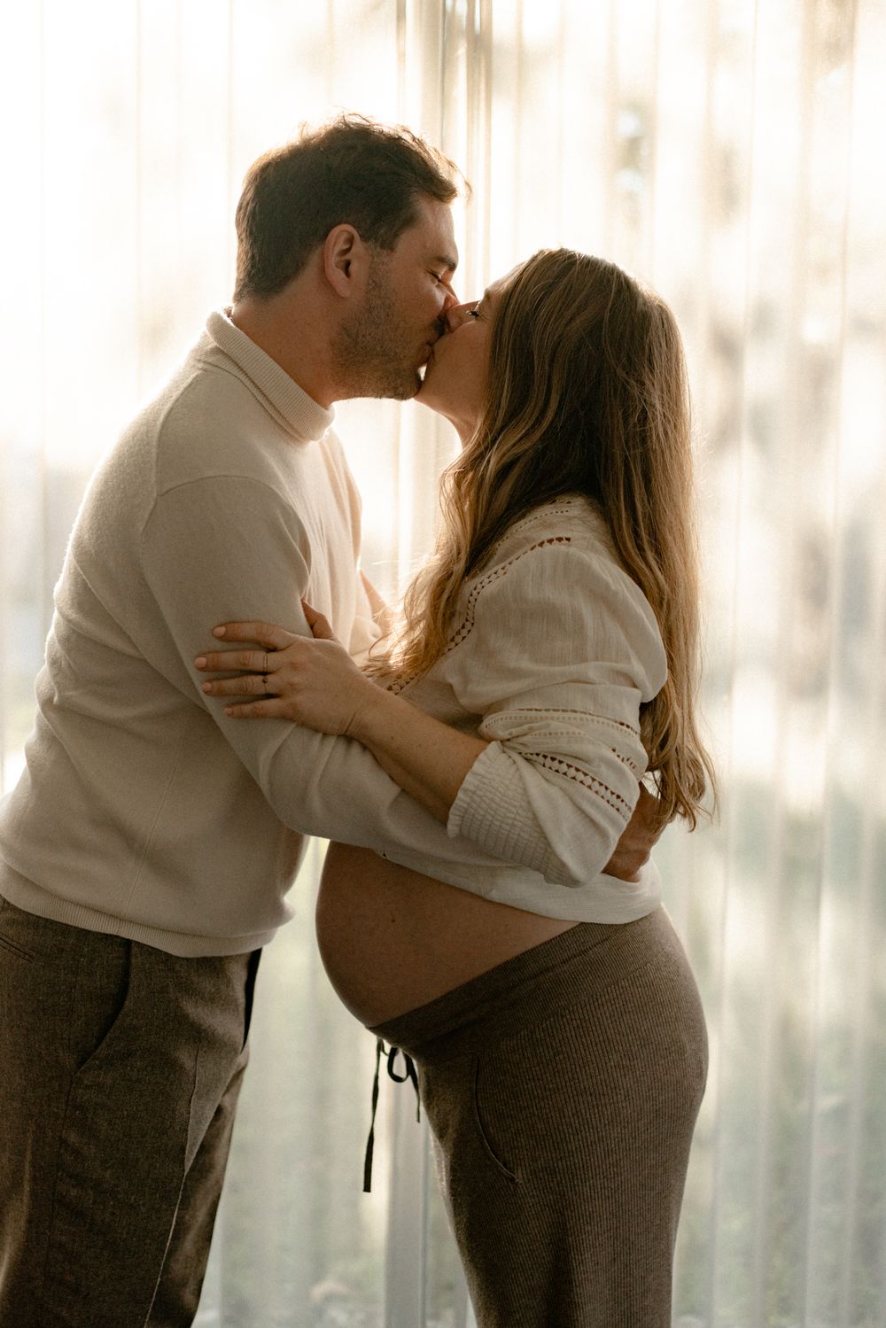 A series of intimate black and white maternity photos showing a couple embracing against a light background.