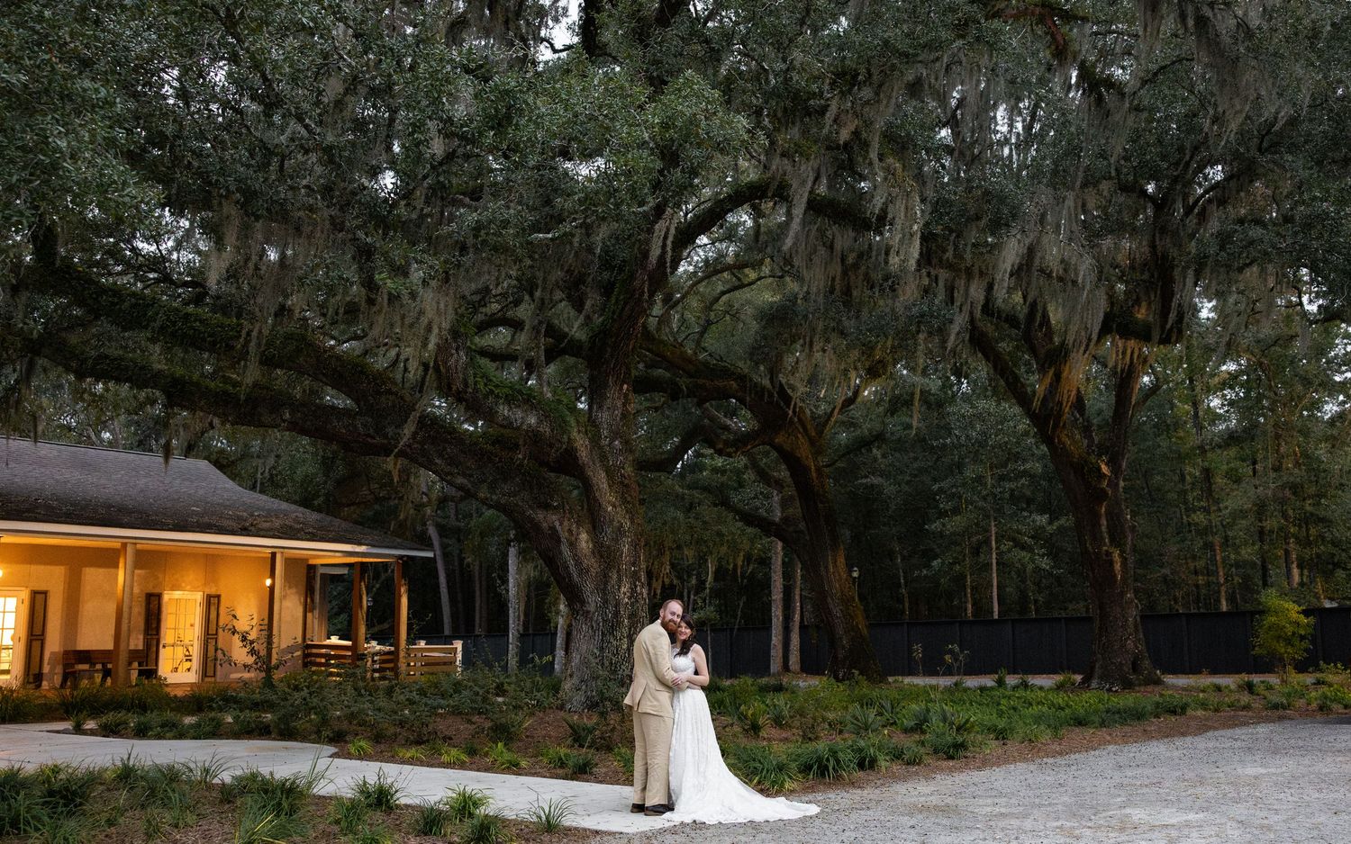A wedding ceremony and reception venue nestled among majestic oak trees with Spanish moss at sunset.