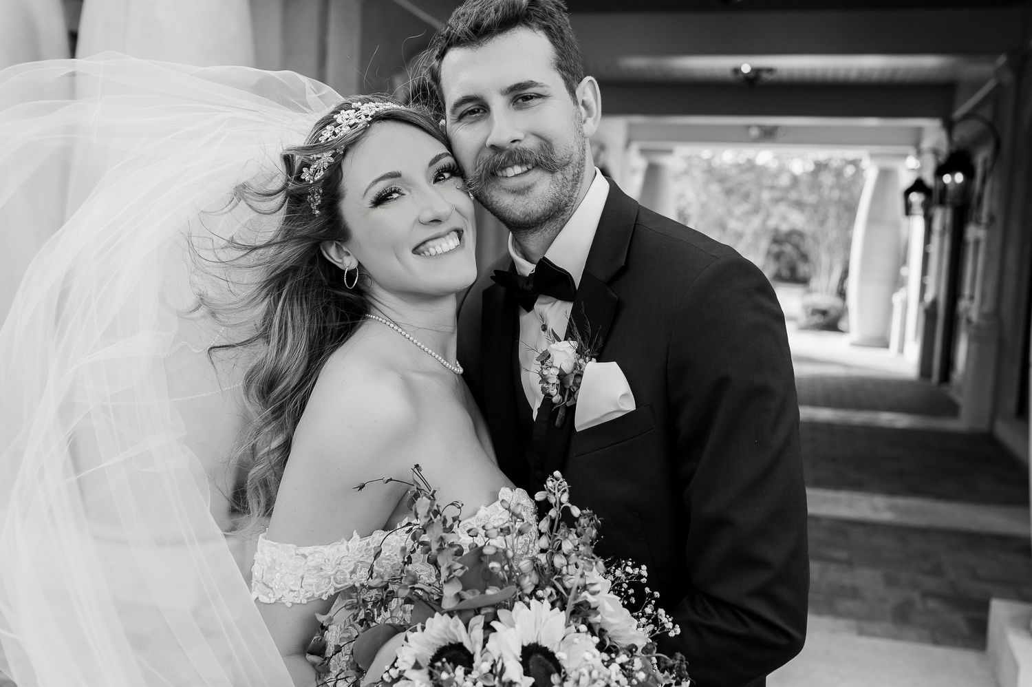 Romantic black and white portrait of newlyweds with bride holding floral bouquet.