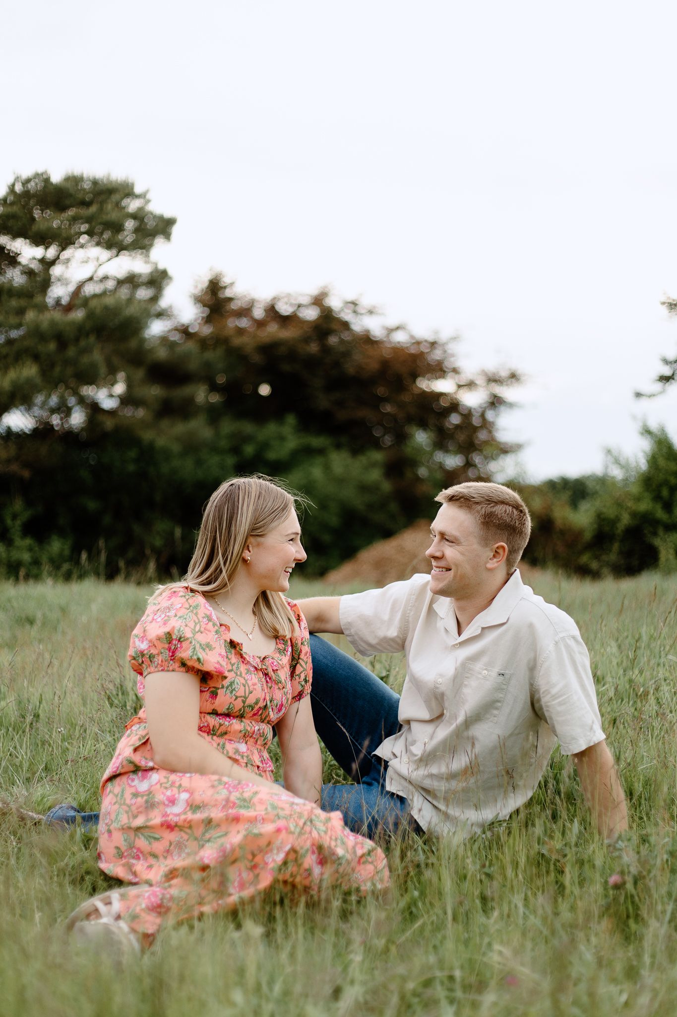 A couple poses together in a lavender field at sunset wearing coordinating white and purple outfits.