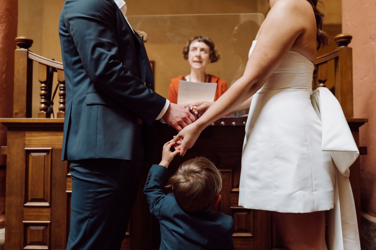 A small child in formal wear holds hands with adults during a courthouse ceremony.