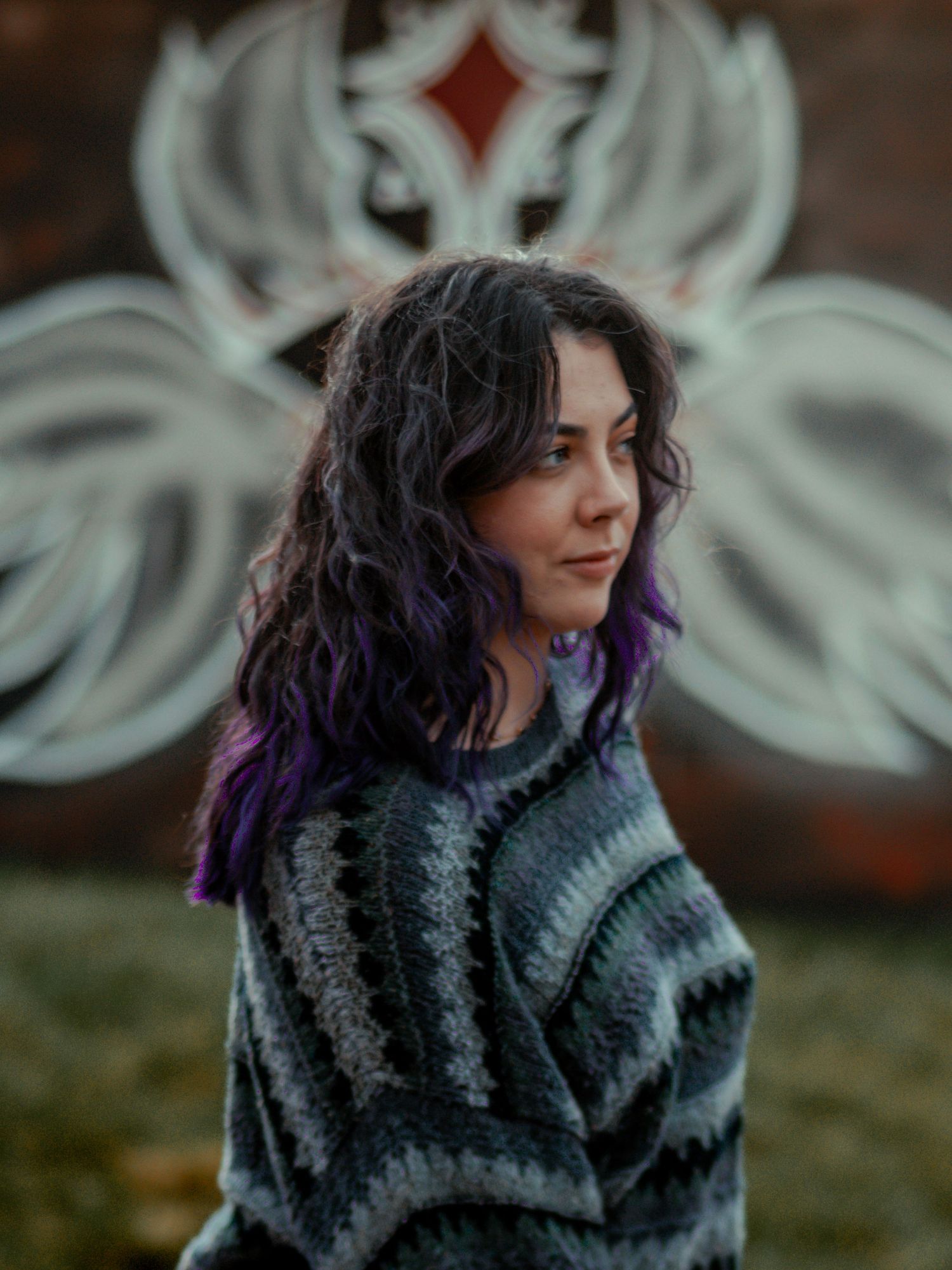 Person wearing a cozy gray sweater with purple-dyed hair tips against a blurred background.