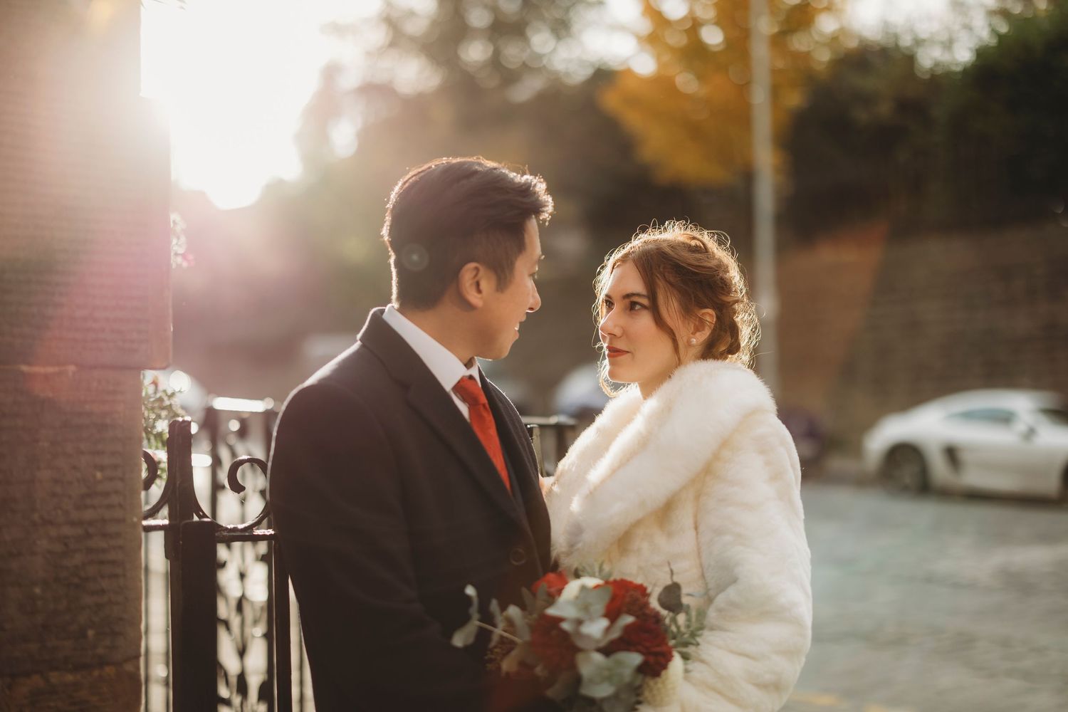 A couple shares an intimate moment while walking along a historic European city street.