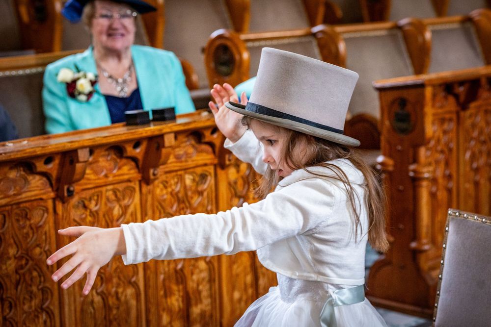 Flower girl wearing oversized top hat holding cane during Southport Town Hall wedding in Merseyside