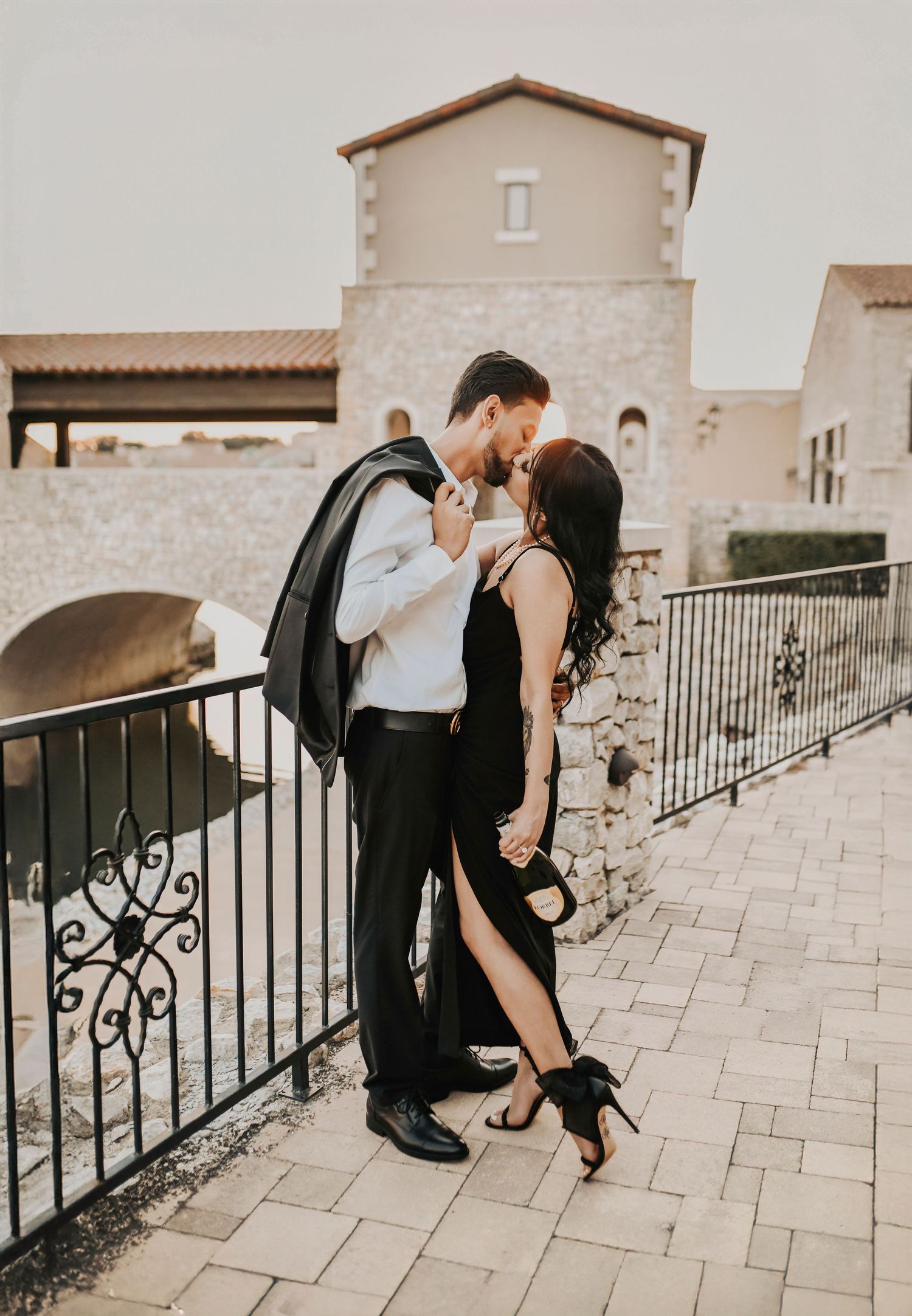 Romantic engagement photo of a couple kissing while drinking champagne at sunset in Westlake, Texas