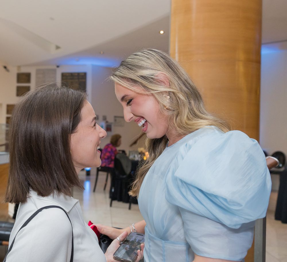 Two people in medical scrubs lean in close to examine something together in a clinical setting.