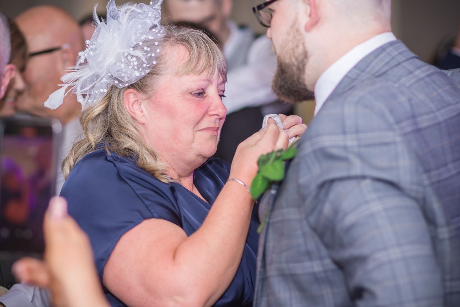 A group of wedding guests dance and celebrate together on a crowded dance floor at a reception party.