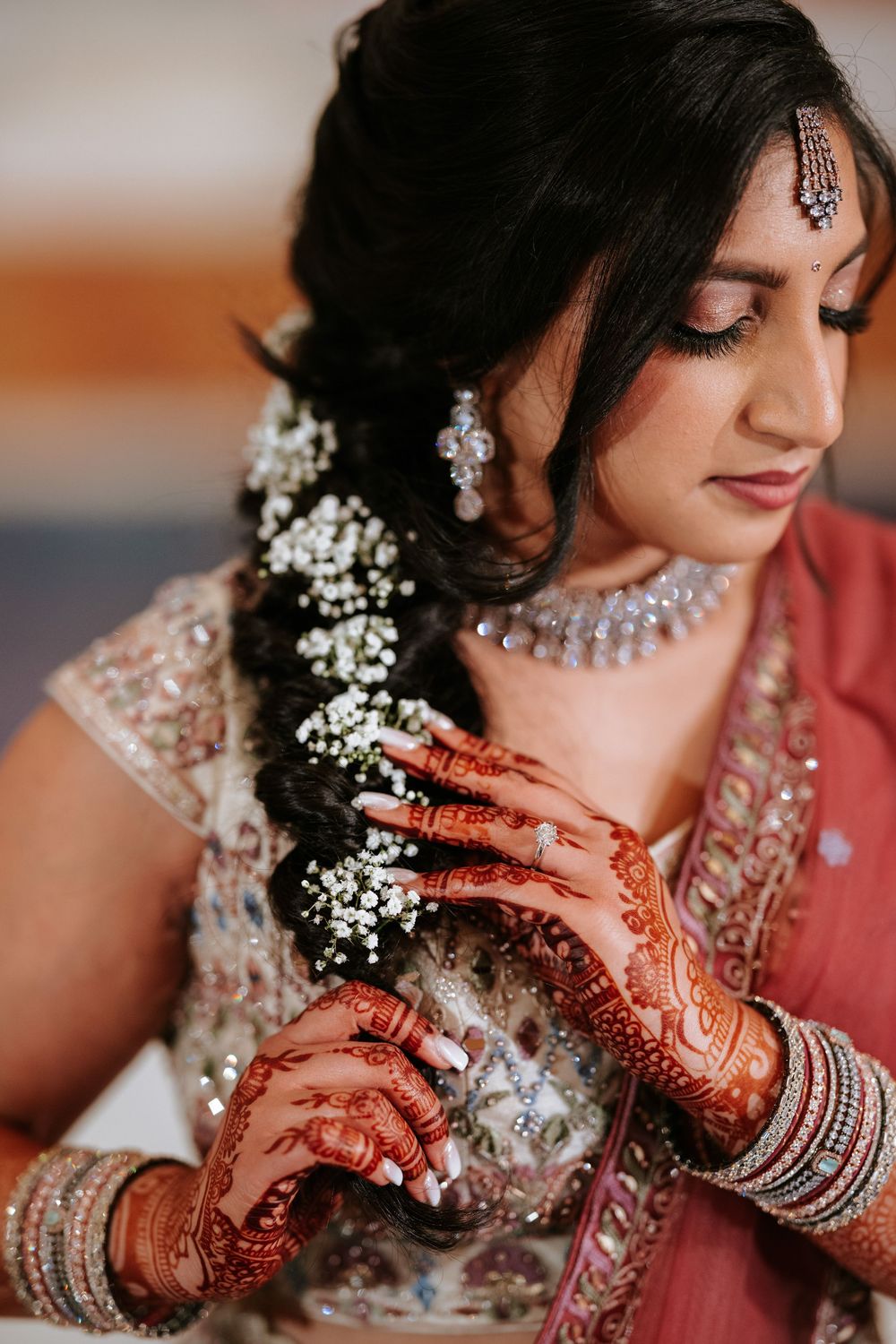 Close-up shots of traditional Indian bridal jewelry and henna-adorned hands with baby's breath flowers in hair.